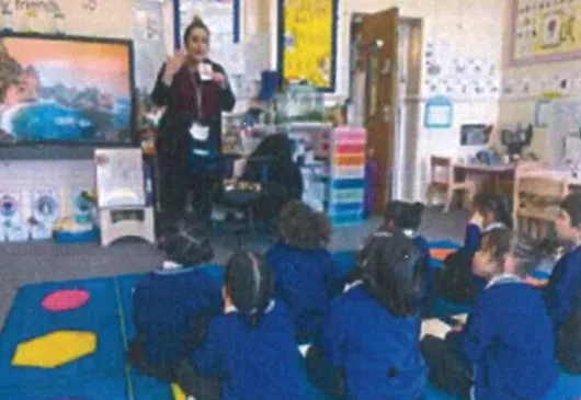 Teacher talking to children who are sitting on a carpet